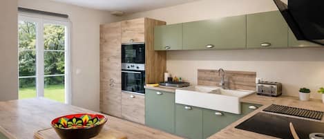 A modern kitchen with a large window, built-in oven, and a sink.