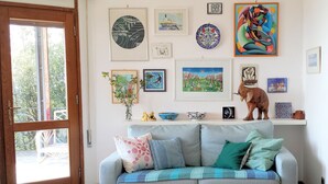 A living room with a grey sofa, a white fluffy rug, and various framed artworks on the wall. - Total Peace, Quiet And Privacy In A Breathtaking Mountainside Location Near Rome (Poggio Catino)
