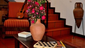A living room with a sofa, a coffee table with a vase of flowers, a guitar, and a staircase. - Luxury villa by the sea with private pool, terrace and sea view (Calheta)