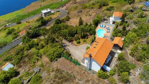 An aerial view of a coastal property with a swimming pool, a road, and surrounding greenery. - Luxury villa by the sea with private pool, terrace and sea view (Calheta)