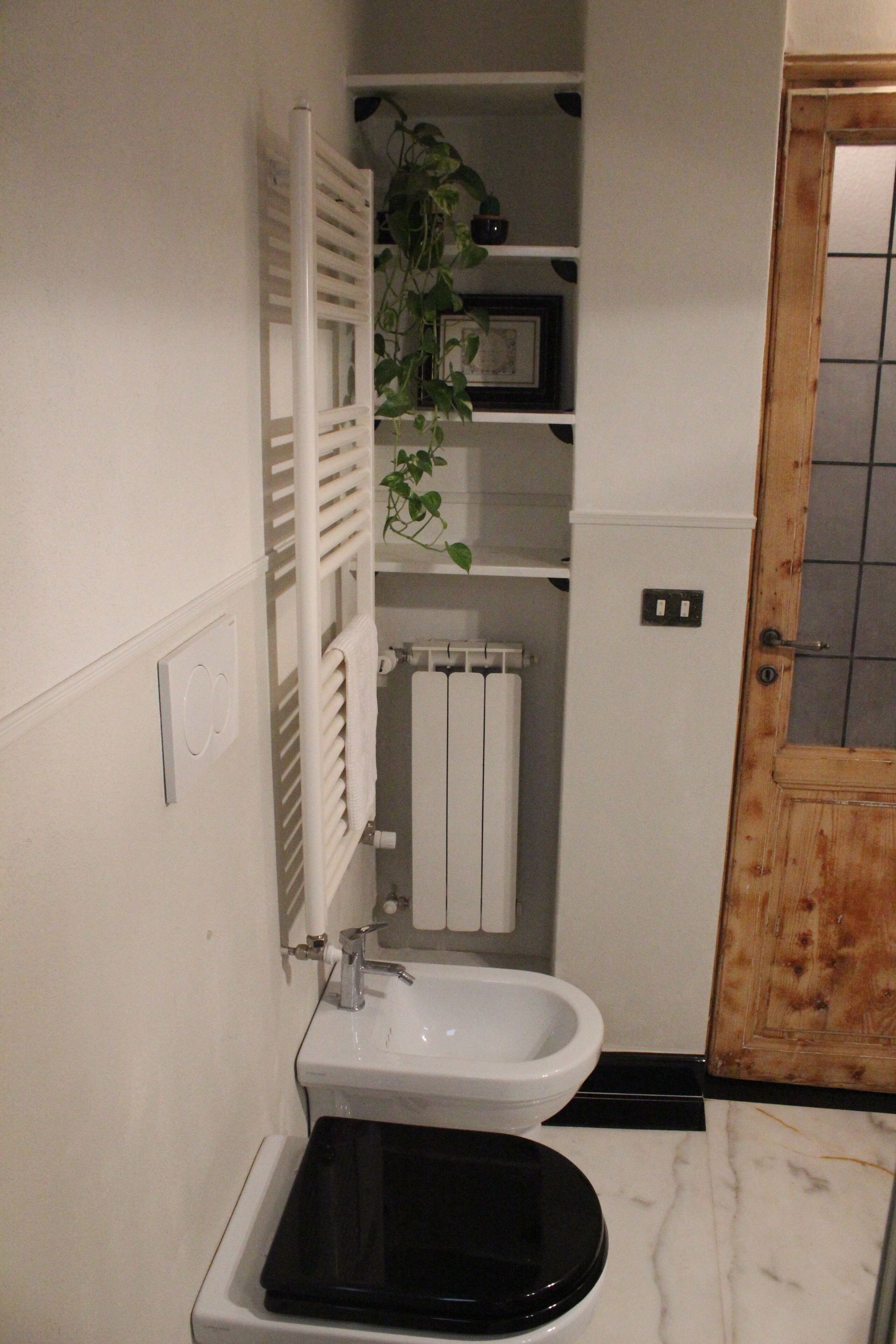 Ein Badezimmer mit Waschbecken in Weiß, Toilette in Schwarz und einem Handtuchhalter.