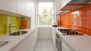 Eine moderne Küche mit weißen Schränken, einer Edelstahlspüle und einem Fenster mit Jalousien.