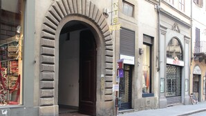 Un edificio con una amplia entrada arqueada, una tienda con persiana baja y una bicicleta estacionada afuera.