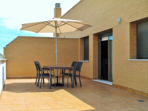 A patio with a table and chairs, an umbrella, and a brick building in the background. - PENTHOUSE, TERRACE ON THE HORIZON OF ALMERIA (Almería)