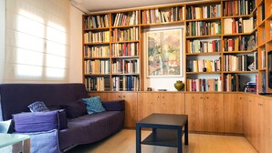 A cozy reading nook with a purple sofa, a small table, and a bookshelf filled with books. - PENTHOUSE, TERRACE ON THE HORIZON OF ALMERIA (Almería)