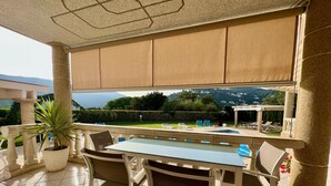 An outdoor patio with a table and chairs, a potted plant, and a view of a pool and mountains. - A spacious 4 bedroom villa, all with en suite bathrooms, large garden & Pool (calonge)