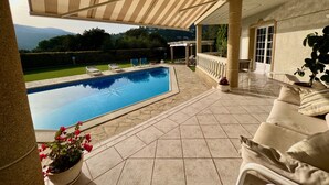 A covered outdoor area with a swimming pool, lounge chairs, and a view of the mountains. - A spacious 4 bedroom villa, all with en suite bathrooms, large garden & Pool (calonge)