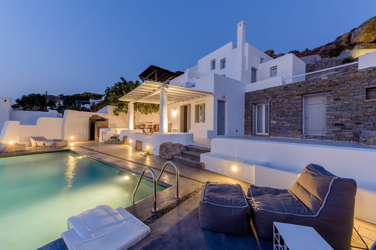 A modern pool area with lounge chairs and a covered seating area.
