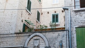 A building with a stone facade, green shutters, and a visible archway. - Luxury Apartment in the heart of Diocletian’s Palace with large private terrace. (Split)