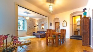 A spacious living area with a stone wall, wooden furniture, and a dining table. - Luxury Apartment in the heart of Diocletian’s Palace with large private terrace. (Split)