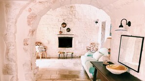 A rustic room with a stone fireplace, wooden furniture, and a stone floor. - At Trullo Sovrano - Rental Home - Air condition and free Wi-Fi (Locorotondo)