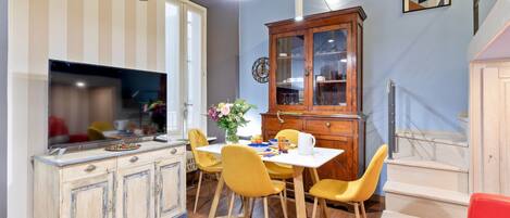 A dining area with a wooden cabinet, yellow chairs, and a white table.