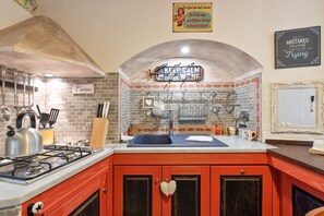Una cocina con armarios rojos, una estufa a gas y un cartel que dice 'Keep Calm and Drink Wine'.