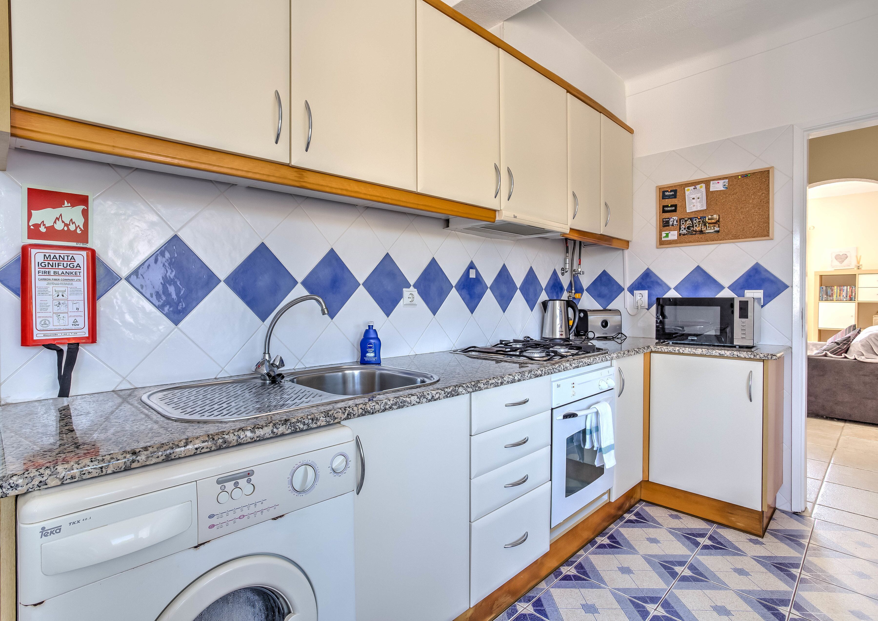 A compact kitchen with a washing machine, a microwave, and a gas stove.