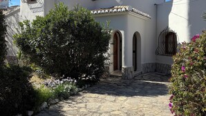 A traditional building with a curved facade, multiple windows with metal grilles, and a stone-paved courtyard.