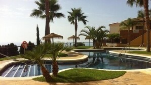 A pool area with palm trees, a gazebo, and a building with a tiled roof. - HOLIDAYS WITH SEA AND MOUNTAIN VIEWS (ALMUÑECAR - GRANADA)