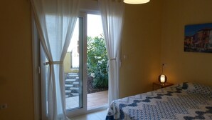 A bedroom with a bed, a nightstand, a lamp, and a view of a garden through a sliding glass door. - HOLIDAYS WITH SEA AND MOUNTAIN VIEWS (ALMUÑECAR - GRANADA)