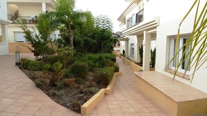 A courtyard with a tiled walkway, surrounded by greenery and residential buildings. - HOLIDAYS WITH SEA AND MOUNTAIN VIEWS (ALMUÑECAR - GRANADA)