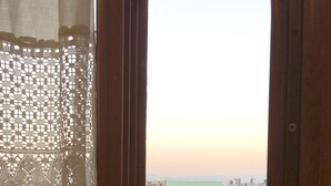 Una habitación con un amplio ventanal que da a un paisaje urbano al atardecer.