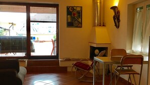 Un comedor con una mesa y sillas, un adorno de pared, un reloj y vistas al exterior por una ventana.