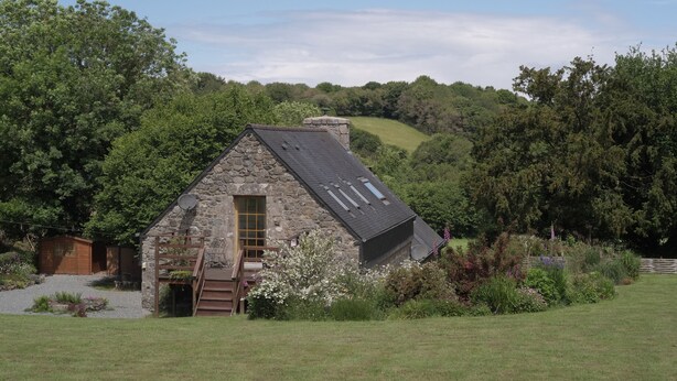 A stone house with a sloped roof, a wooden door, and a small porch. - Traditional Breton Longere, Cotes d'Armor (La Chapelle-Neuve)