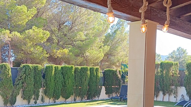 Un espace extérieur abrité comprenant une piscine, des chaises et des plantes en pot.