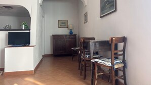 A dining area with a table and chairs, a television, a cabinet, and a framed picture on the wall. - Sea house, garden with a view (Tropea)