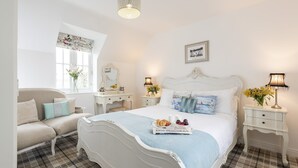 Une chambre à coucher avec un grand lit, une table de chevet, une commode, une chaise et une fenêtre avec des rideaux.
