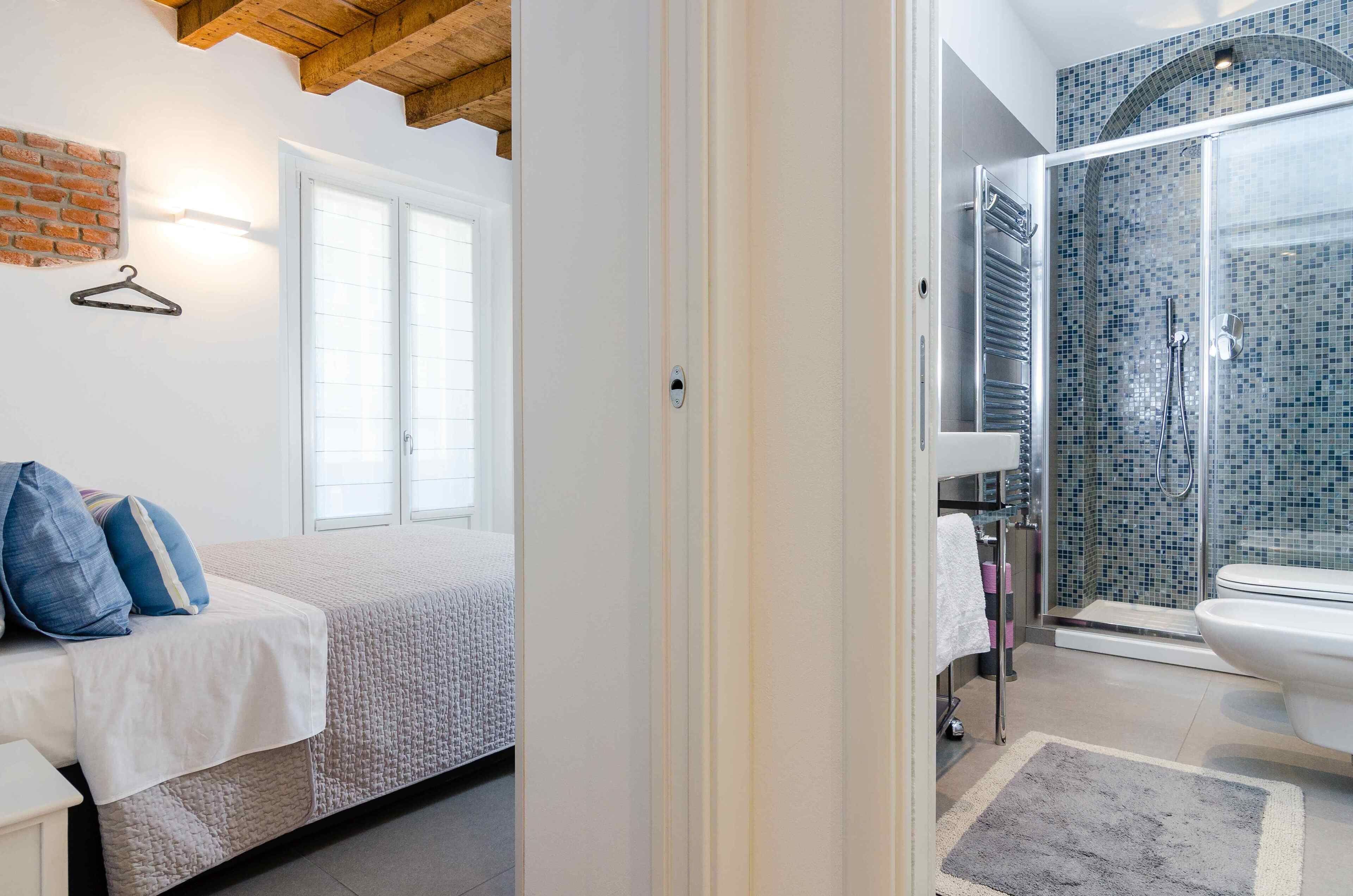 Un dormitorio con cama, una lámpara colgante y una ventana.