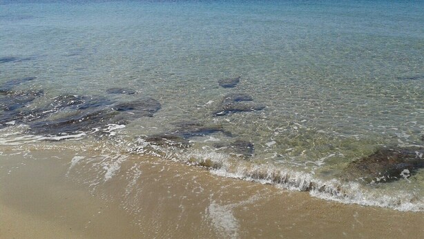 Una playa con agua cristalina y una isla en la distancia.