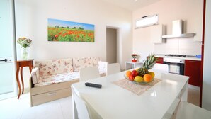 Una cocina moderna con armarios blancos, una mesa de comedor con fruta y un sofá estampado con motivos florales.