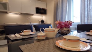 A modern kitchen with a microwave, stove, and sink. There are two blue chairs and a glass table with a vase of pink flowers. - 3 beds/3 baths, 3 min. walking to the Vatican Museums, metro station, FREE WIFI (Roma)