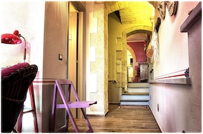 A narrow hallway with a wooden floor, a red chair, a purple chair, and a red lamp. - Memorable sunsets from the terraces of the house in the village of Cuglieri (Cuglieri)