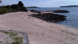 Ein Kiesstrand mit Felsformationen und ruhigem Wasser.