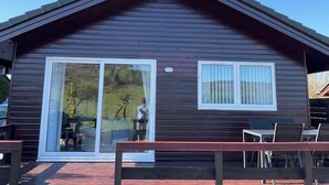 Eine Holzhütte mit einer großen Schiebeglaswand und einem kleineren Fenster.