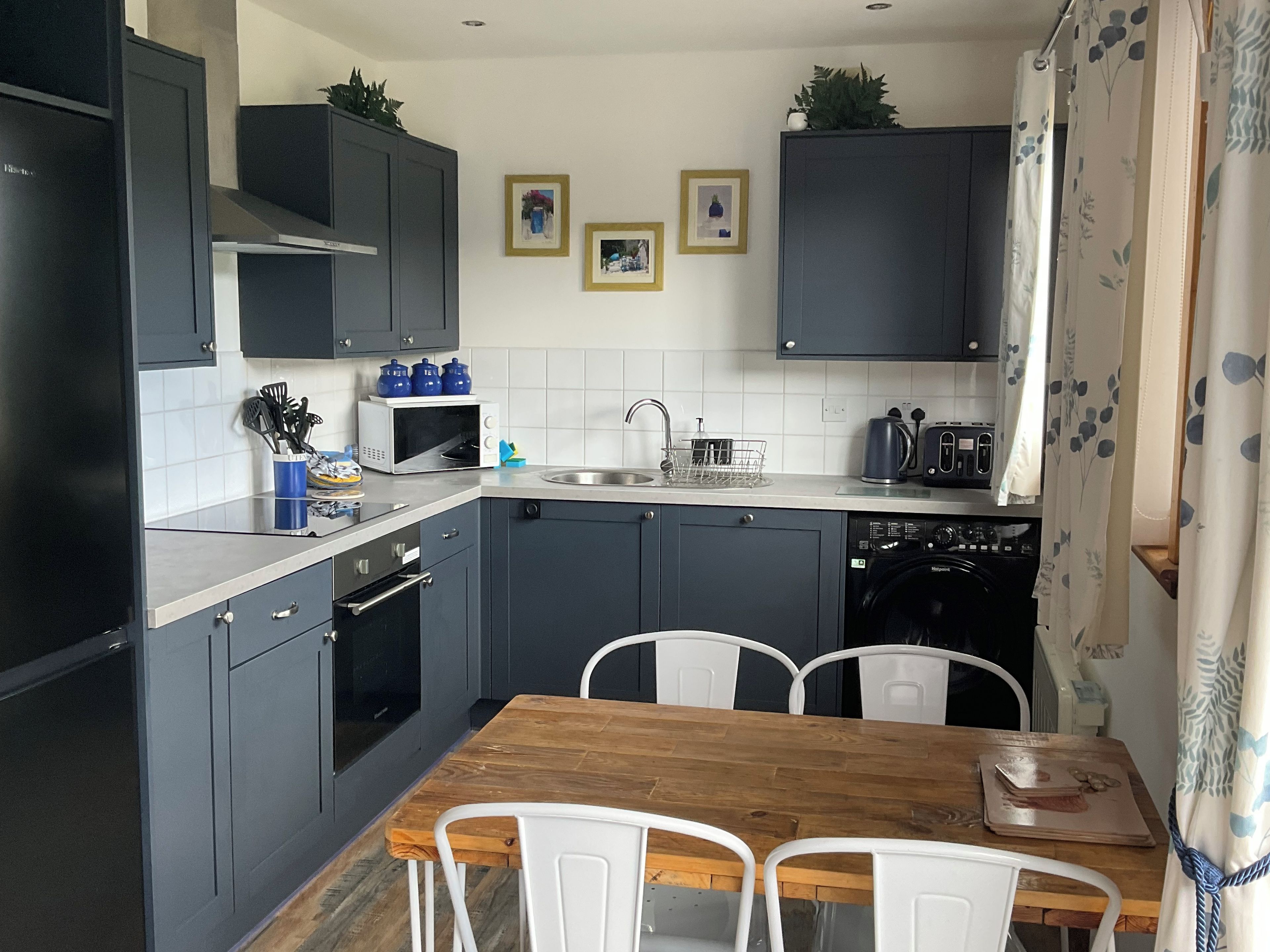 A modern kitchen with grey cabinets, a wooden dining table, and white chairs.