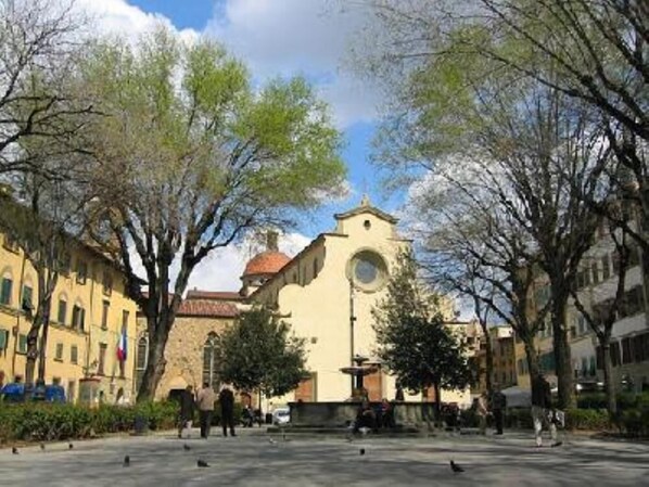A square with a central fountain, surrounded by trees and buildings with traditional architecture.