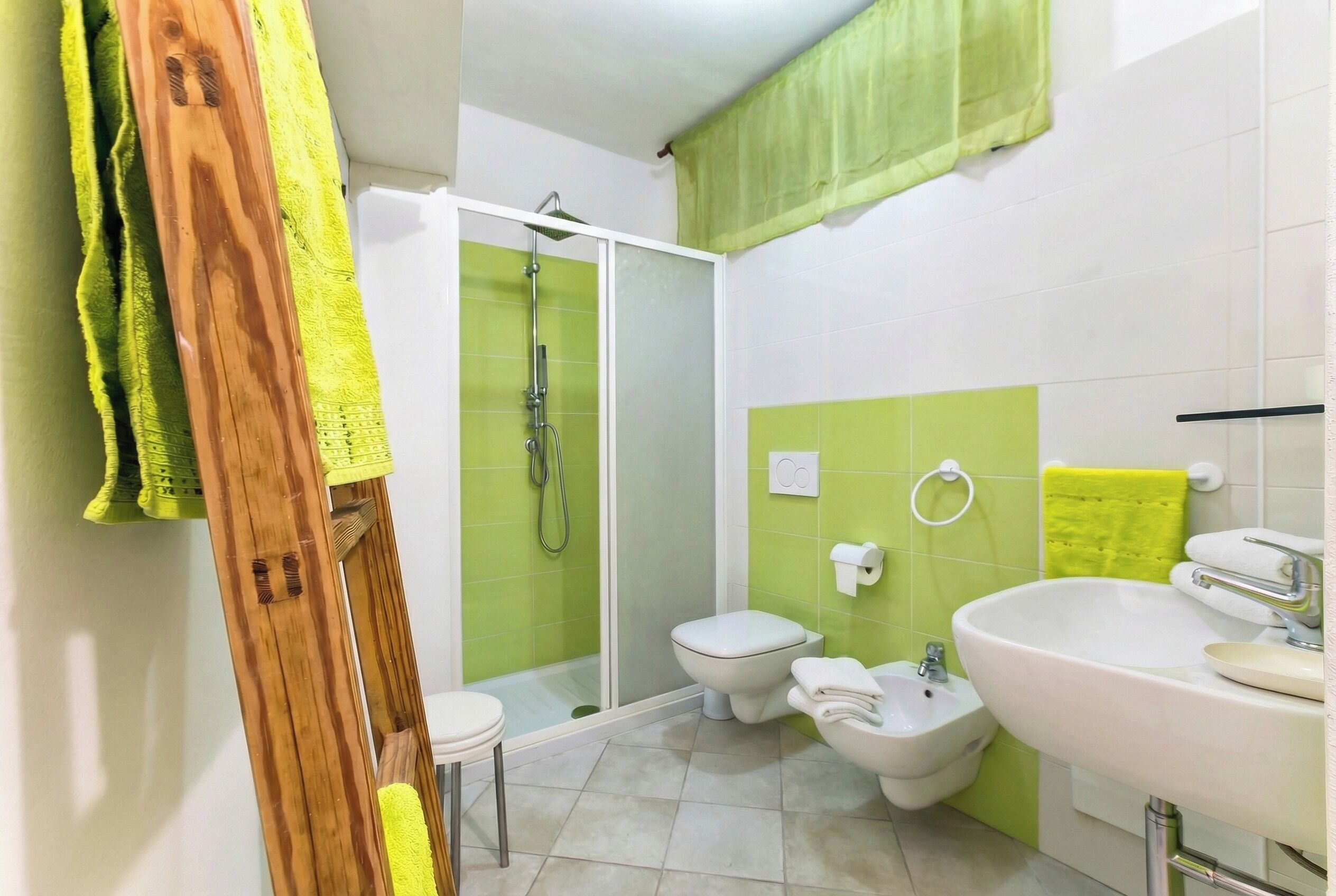 A bathroom with a shower, toilet, bidet, and sink.