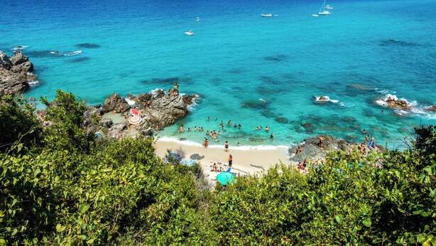 A coastal beach with clear turquoise waters, rocky formations, and people enjoying the beach and water. - ClickSardegna Villa Flavia with seafront terrace in the Porto Conte Nature Park (Alghero)