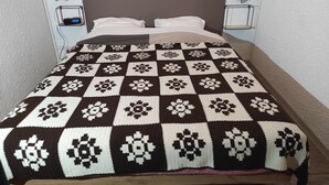 A bed with a checkered blanket, two bedside tables with lamps, and a digital clock.