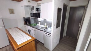 A compact kitchen with a washing machine, a sink, and a microwave.
