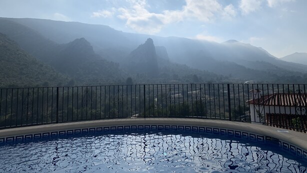 En pool med udsigt til bjerge og en overskyet himmel.