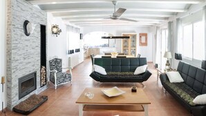 En rummelig stue med pejs, en stol med zebra-mønster, en mørkegrøn sofa og et træbord.