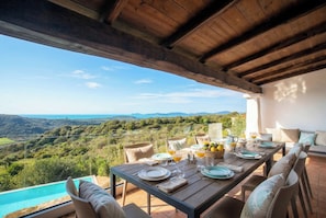 An outdoor dining area with a table set for two, overlooking a scenic landscape. - ClickSardegnaSeafront villa, 5 bedrooms, 6 bathrooms, infinity pool, WiFi (Alghero)