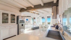 A modern kitchen with white cabinetry, a stainless steel refrigerator, and a large window overlooking a scenic view.