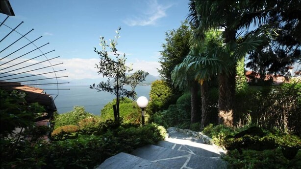 A stone pathway leading to a scenic overlook with a view of the sea and mountains.