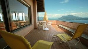 A balcony with yellow chairs, a table, and an umbrella.