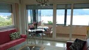 A living room with a red sofa, a glass coffee table, and a dining area with a table and chairs.