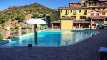 Relax by the serene pool surrounded by a paved deck and multi-story buildings with Mediterranean architecture.