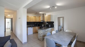 Una cocina moderna con armarios de madera, una isla central y un comedor con mesa y sillas.
